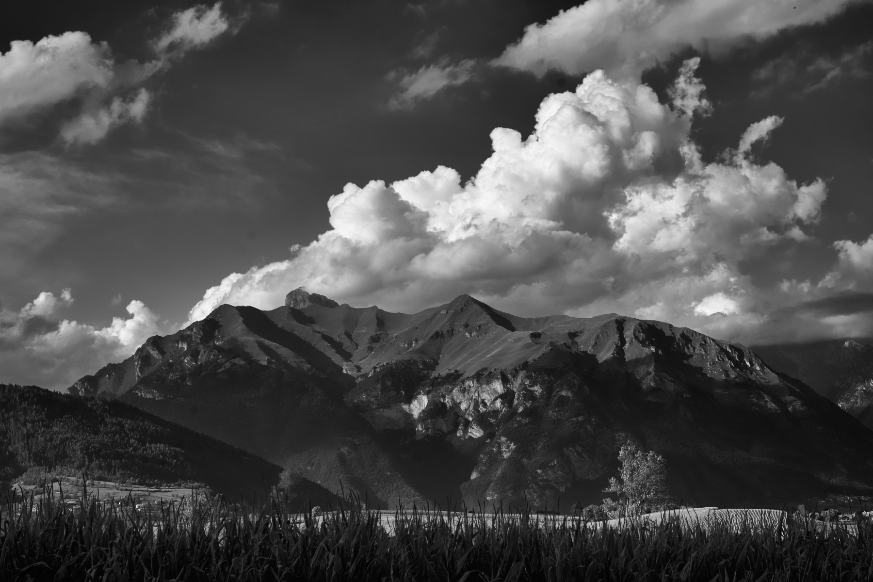Profilo delle montagne sotto grandi nuvole, in bianco e nero