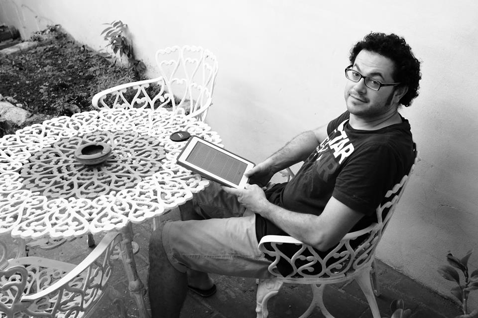 Francesco seduto a un tavolo in giardino con un tablet, in bianco e nero
